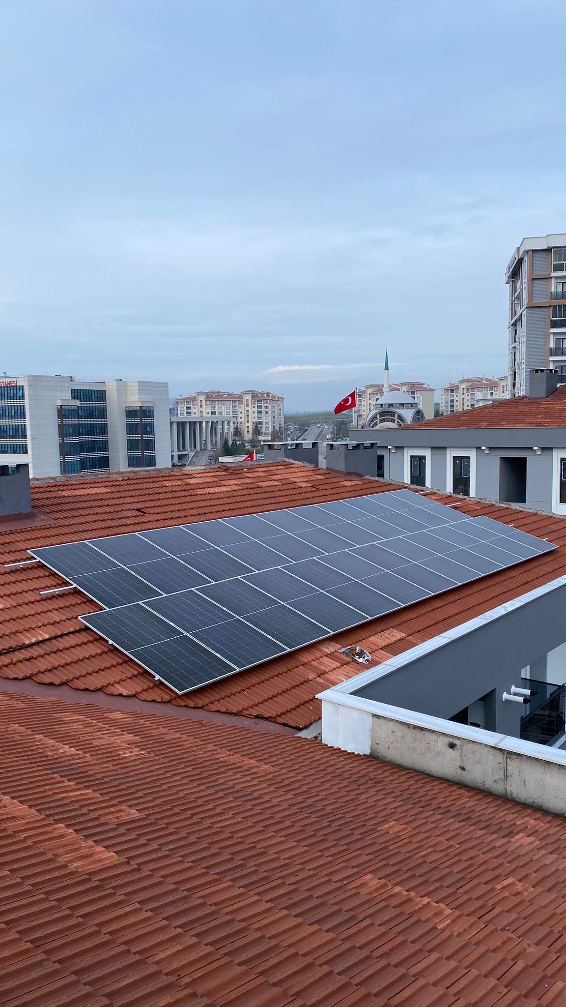 Kiremit çatı güneş panelleri, Türk bayrağı ve şehir manzarası - Solanka Enerji