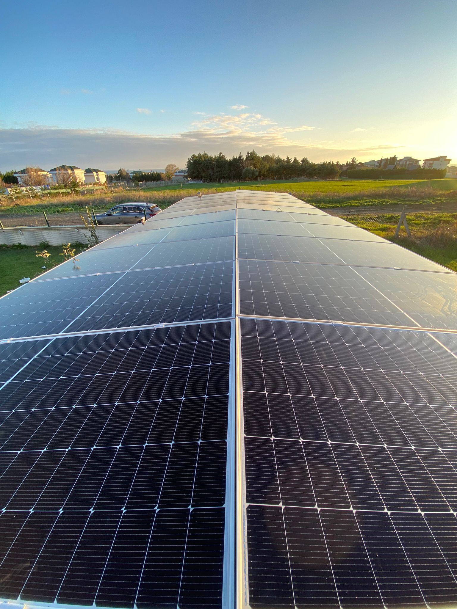 Gün batımında çatı güneş panelleri, rüzgar türbinleri - Solanka Enerji